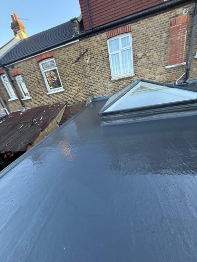View of a flat roof with a skylight, surrounded by brick buildings.