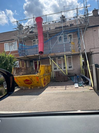 House under renovation with scaffolding and construction equipment in the front garden.