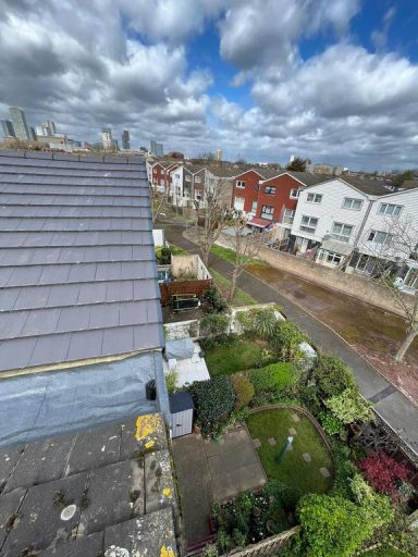 A view of a residential area with houses and gardens under a partly cloudy sky.