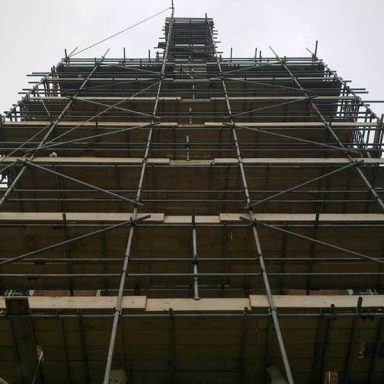 Scaffolding structure surrounding a tall building under construction.